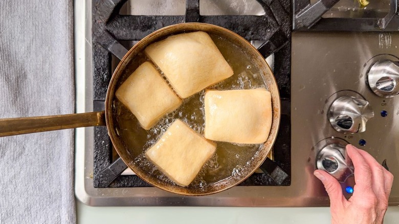 Frying beignets in hot oil in pot on stovetop