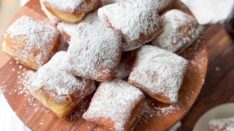 Sugar-coated beignets on wooden platter