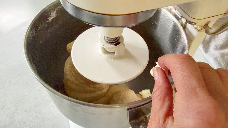Adding butter pieces to beignet dough in stand mixer bowl