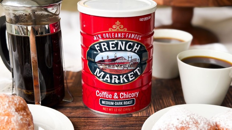 French Market chicory coffee can with a French press, beignets, and coffee cups
