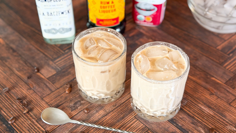 Classic White Russian cocktails in rocks glasses with spoon and liqueur bottles