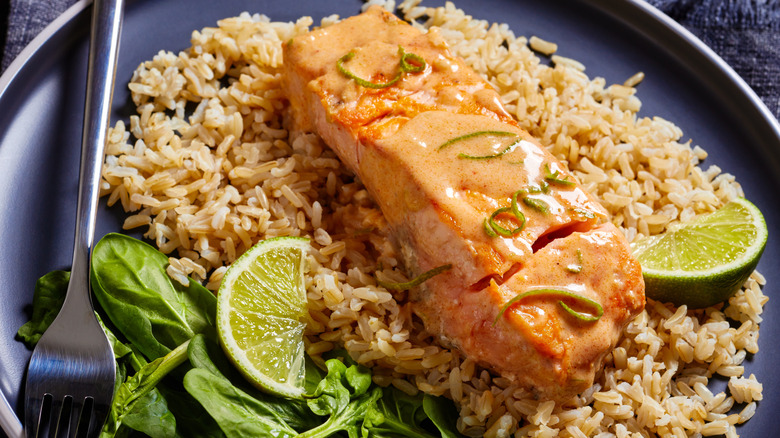 piece of salmon over brown rice with spinach and lime