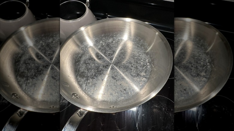 Cloudy mineral deposits on a stainless steel pan.