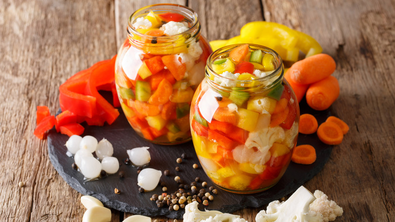 Jars of freshly pickled giardiniera veggies sit on a piece of slate