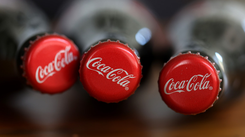three coca cola bottle caps