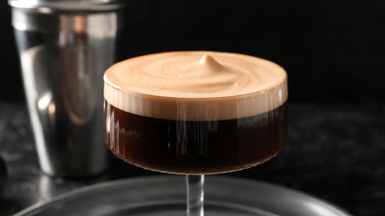 An espresso martini's layers of liquid and foam are seen in close-up.