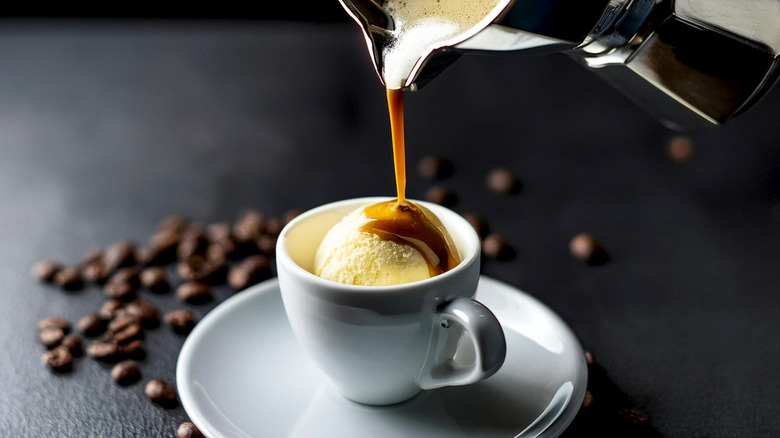 A coffee pot pouring coffee into an espresso cup with vanilla ice cream