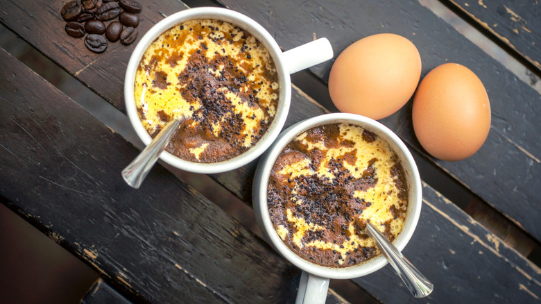 Two cups of cà phê trứng (Vietnamese egg coffee) with eggs on a wooden table