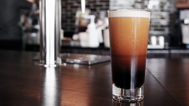 A glass of nitro cold brew coffee on a bar