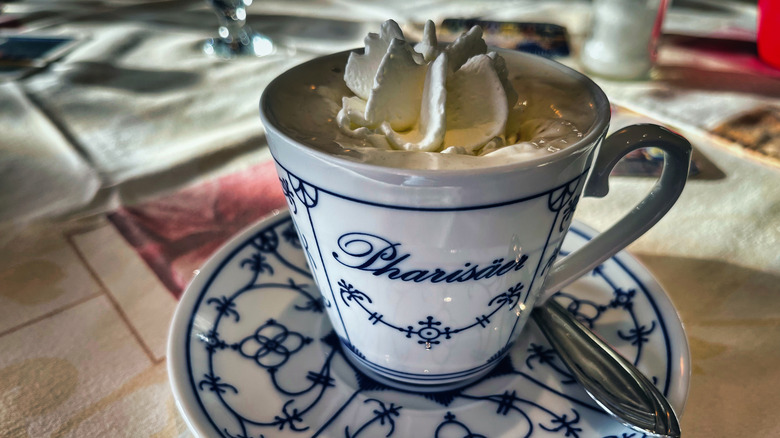 A pharisäer coffee drink topped with whipped cream in a blue and white china cup with matching saucer