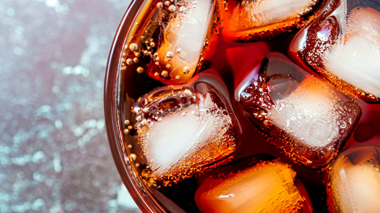 A view from atop a glass filled with ice and a soda which could be Coke or Pepsi