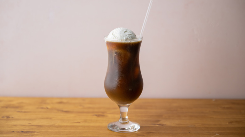 An iced coffee float in a fluted glass with a straw