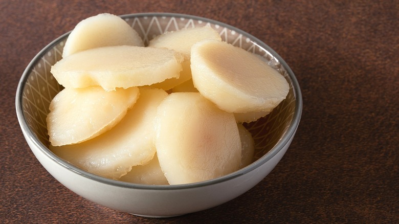 Sliced water chestnuts in a small, patterned bowl over a brown-speckled surface
