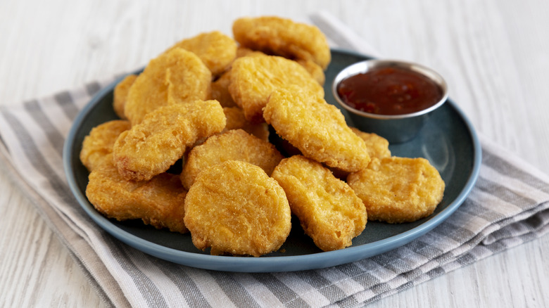 Chicken nuggets on a black plate with a side of sauce.