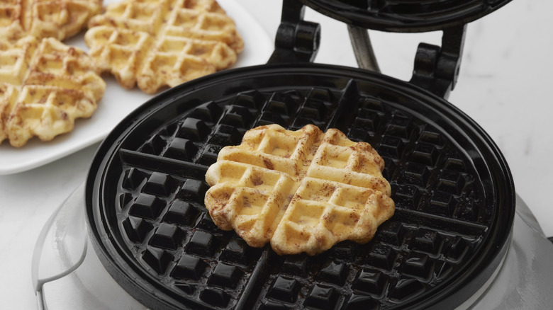 Mini waffle cooked in the center of a round waffle iron.