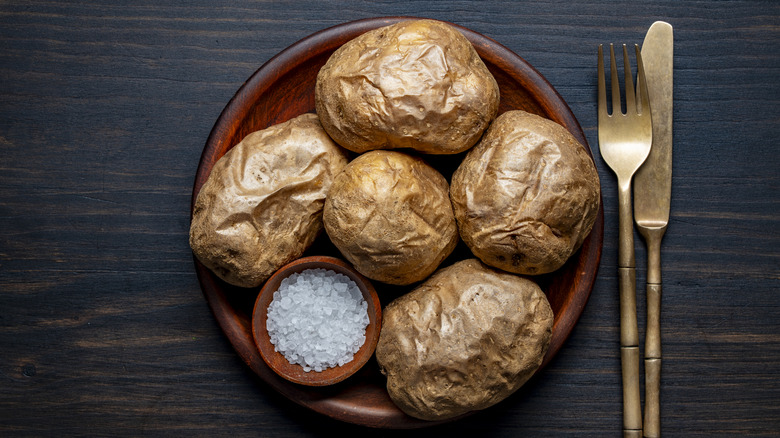 A plate of baked potatoes photographed from above.