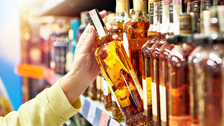 Person holding a bottle of alcohol in a store