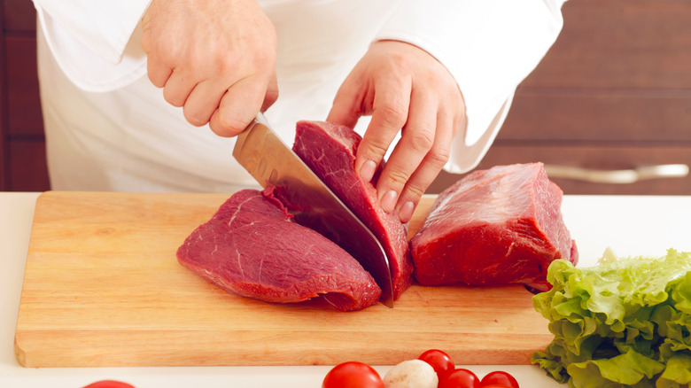 Chef cutting red meat