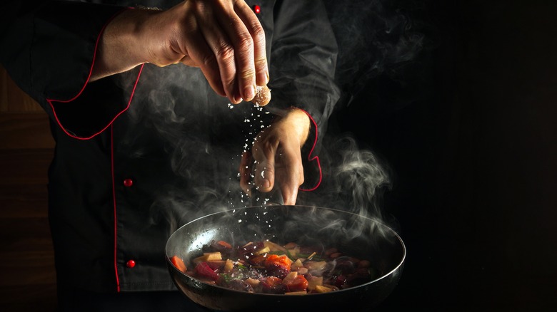 Chef salting pan of food