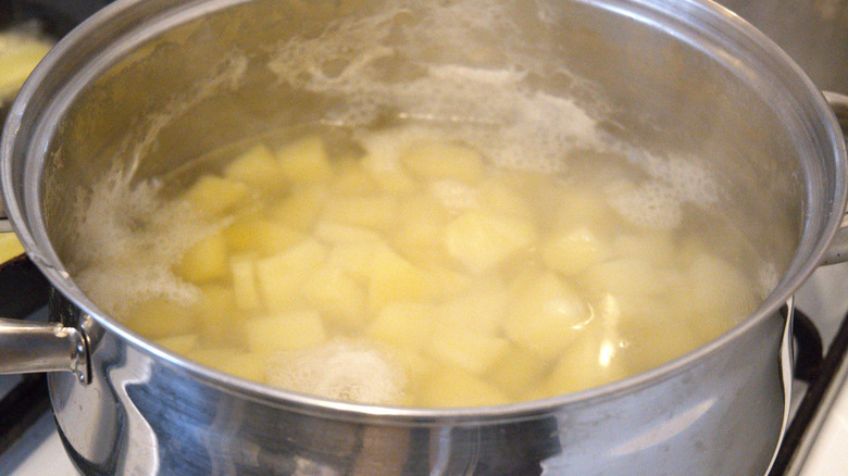 A pot of potatoes boils on the stove.
