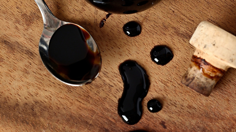 Drops of aged balsamic on a spoon and a wooden table