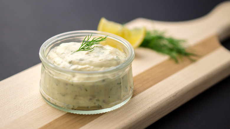 Tartar sauce in a glass container topped with dill.