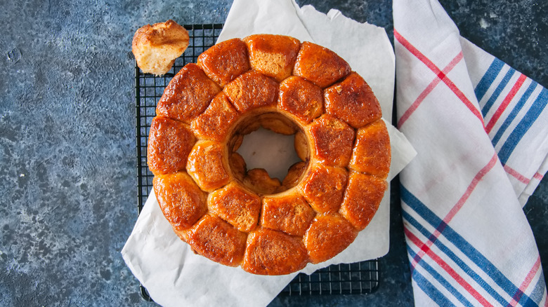 Homemade caramel monkey bread with brown sugar resting on a cooling tray on a blue stone background