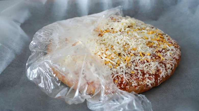 Frozen cheese pizza still wrapped in plastic
