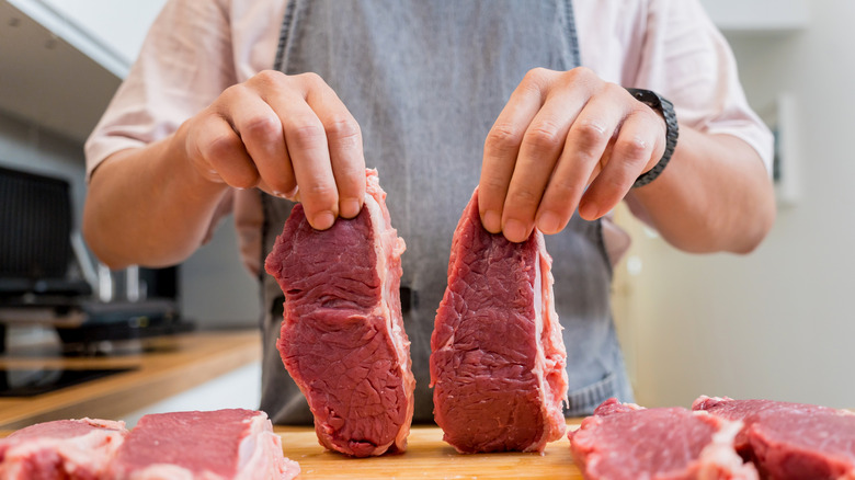 Home cook holding raw steak filets