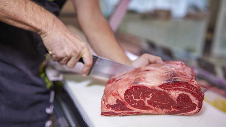Butcher carving raw sirloin steak