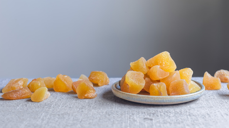 candied ginger pieces on a small plate and on a table