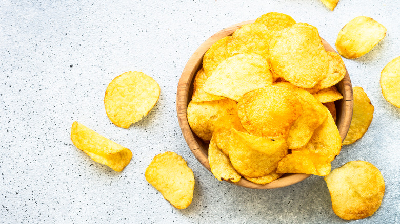 a bowl of potato chips on a white surface