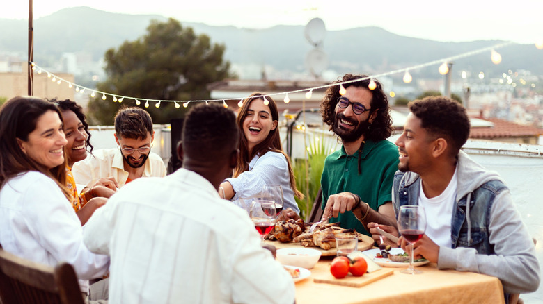 Friends laughing and eating at a dinner party