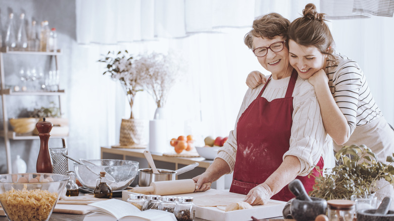 A granddaughter hugging a grandmother as they cook in the kitchen together