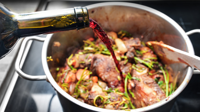 someone deglazing their pot with a splash of red wine