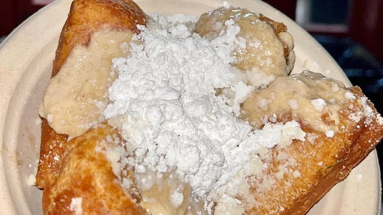 Four beignets topped with banana and powdered sugar