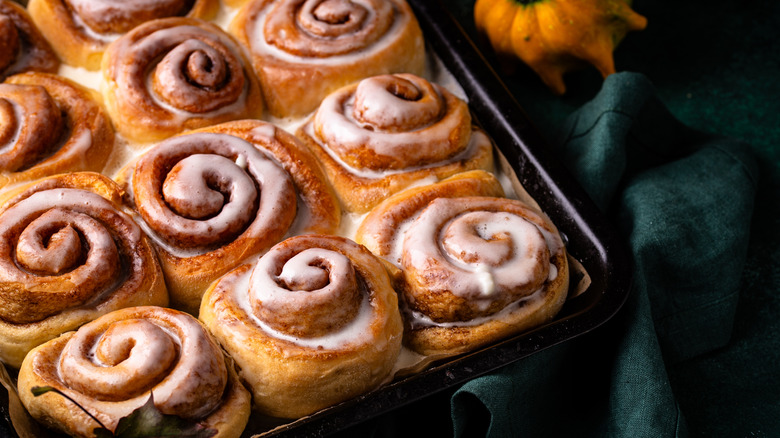 A close-up of a tray of cinnamon buns on a green tablecloth