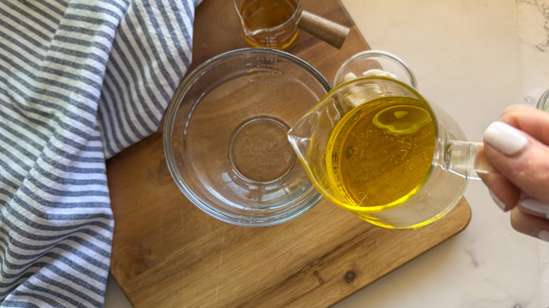 hand pouring oil in bowl