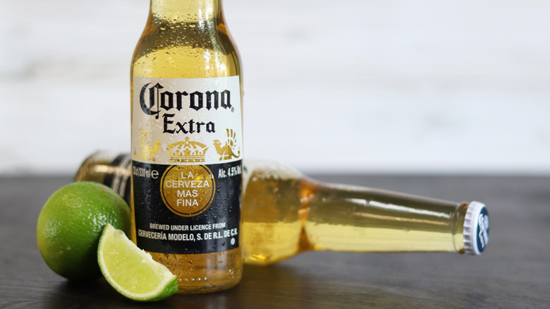 Two bottles of Corona beer with a whole lime and a lime wedge