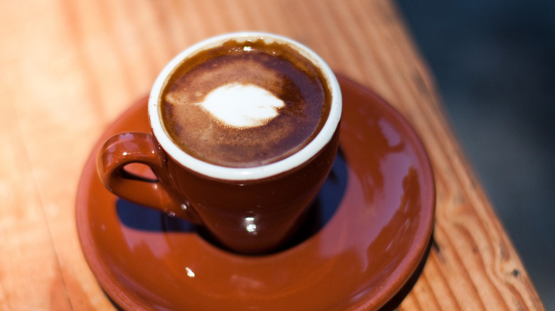 A macchiato in a brown espresso cup.