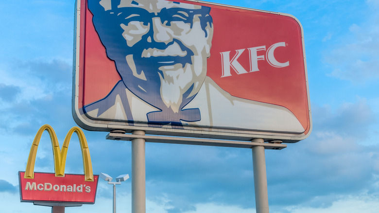 McDonald's and KFC signs in the same image, blue sky in the background