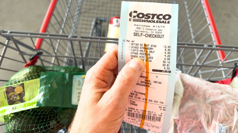 A hand holding a Costco receipt