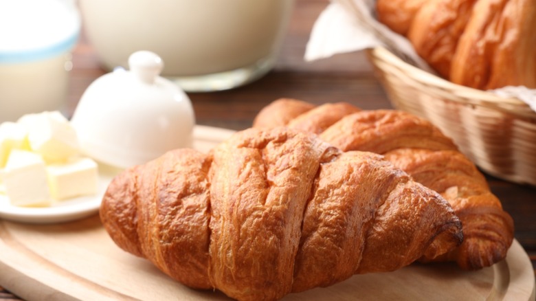 A close-up photo of a croissant on a cutting board with butter.