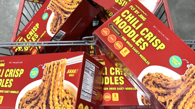 Boxes of Fly By Jing Chili Crisp Noodles stacked in a Costco shopping cart