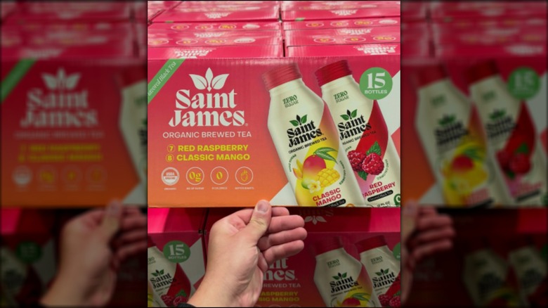 a person's hand in front of a box of Saint James Organic Brewed Tea at Costco