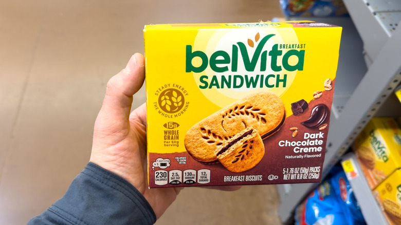 Person's hand holding a box of BelVita sandwich bars with dark chocolate creme filling