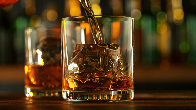 Whiskey being poured into a glass with ice