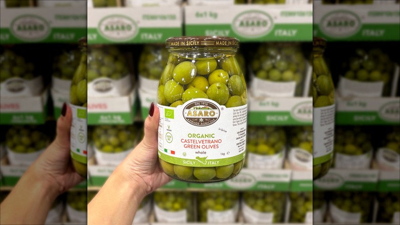 Person holding up a jar of Asaro Organic Green Castelvetrano Olives at Costco