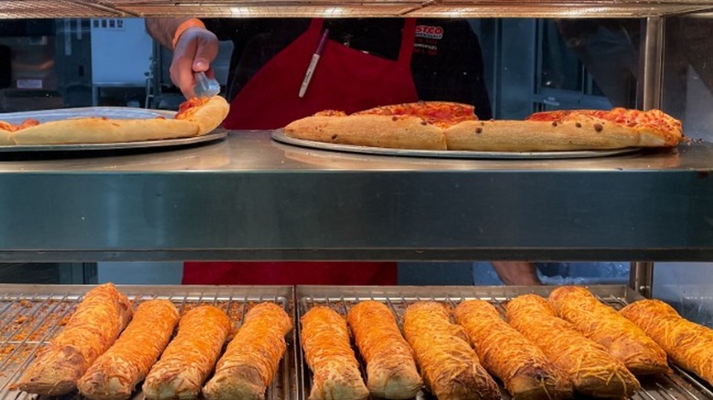 A row of fresh Costco chicken bakes lined up under heaters in the food court.