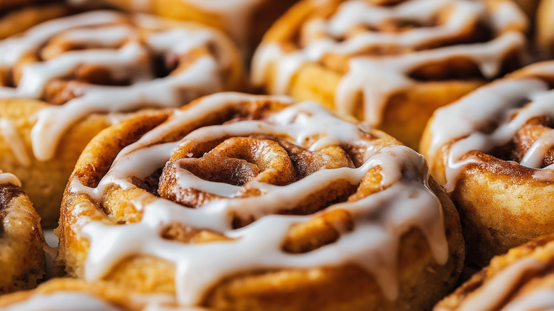 Closeup of several cinnamon rolls covered with frosting